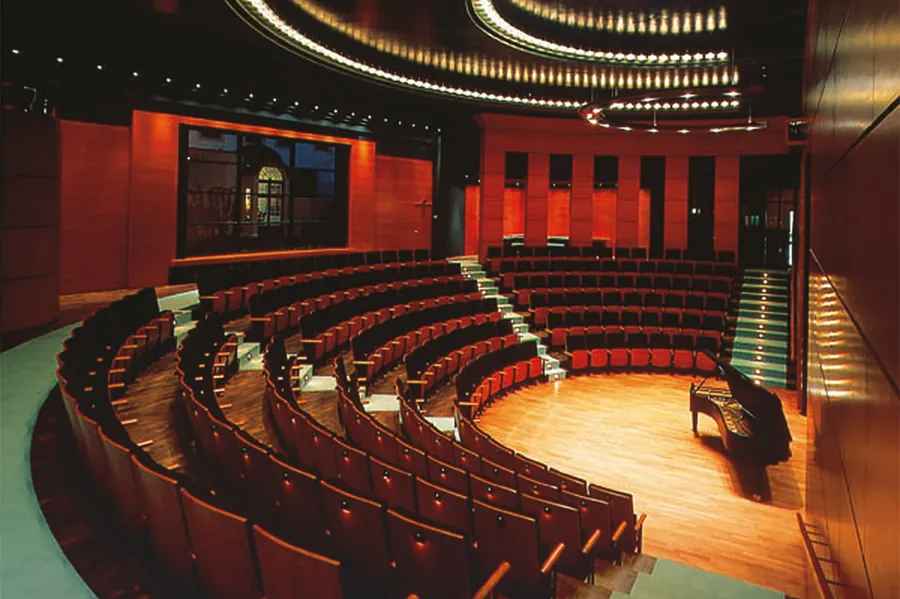 Der Kammermusiksaal erstrahlt in einem warmen rötlichen Holzton. Die 199 Plätze sind in sechs aufsteigenden Halbkreisen um die Bühne angeordnet. Treppen und Flur sind mit einem türkisfarbenen Teppich belegt.
