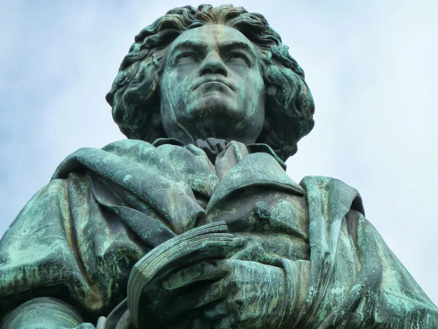 Chest and head of the Bonn Beethoven monument on Münsterplatz, viewed from below against the sky.