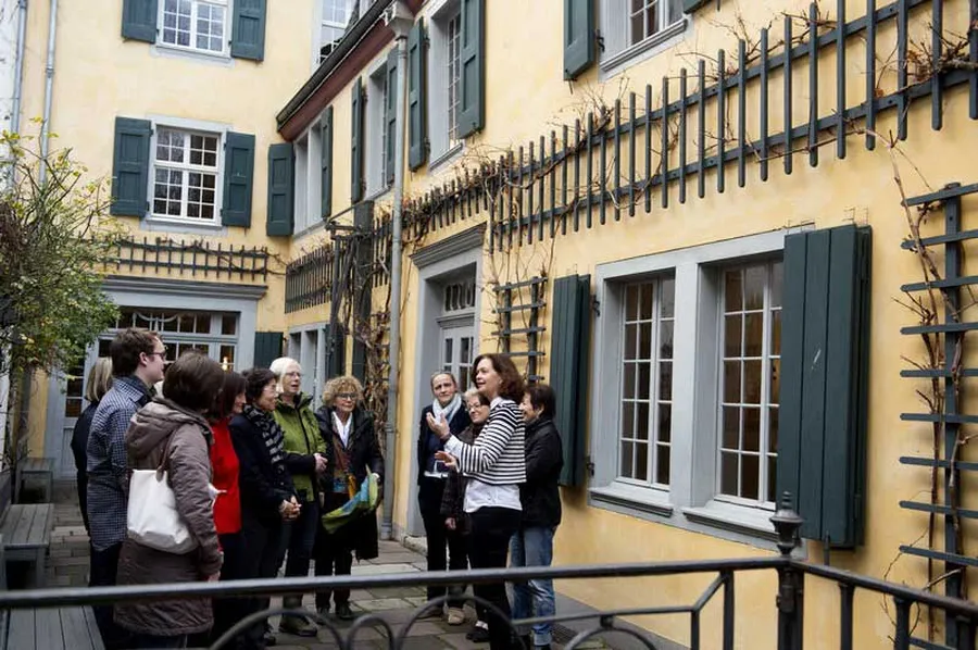 In the museum courtyard in front of the yellow-painted rear building, the actual home of the Beethoven family, a group of visitors stands and listens to the guide.